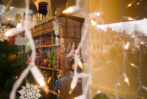 Reflection of a Christmas parade in a craft shop window, highlighting civic pride in Woodstock, Vermont.