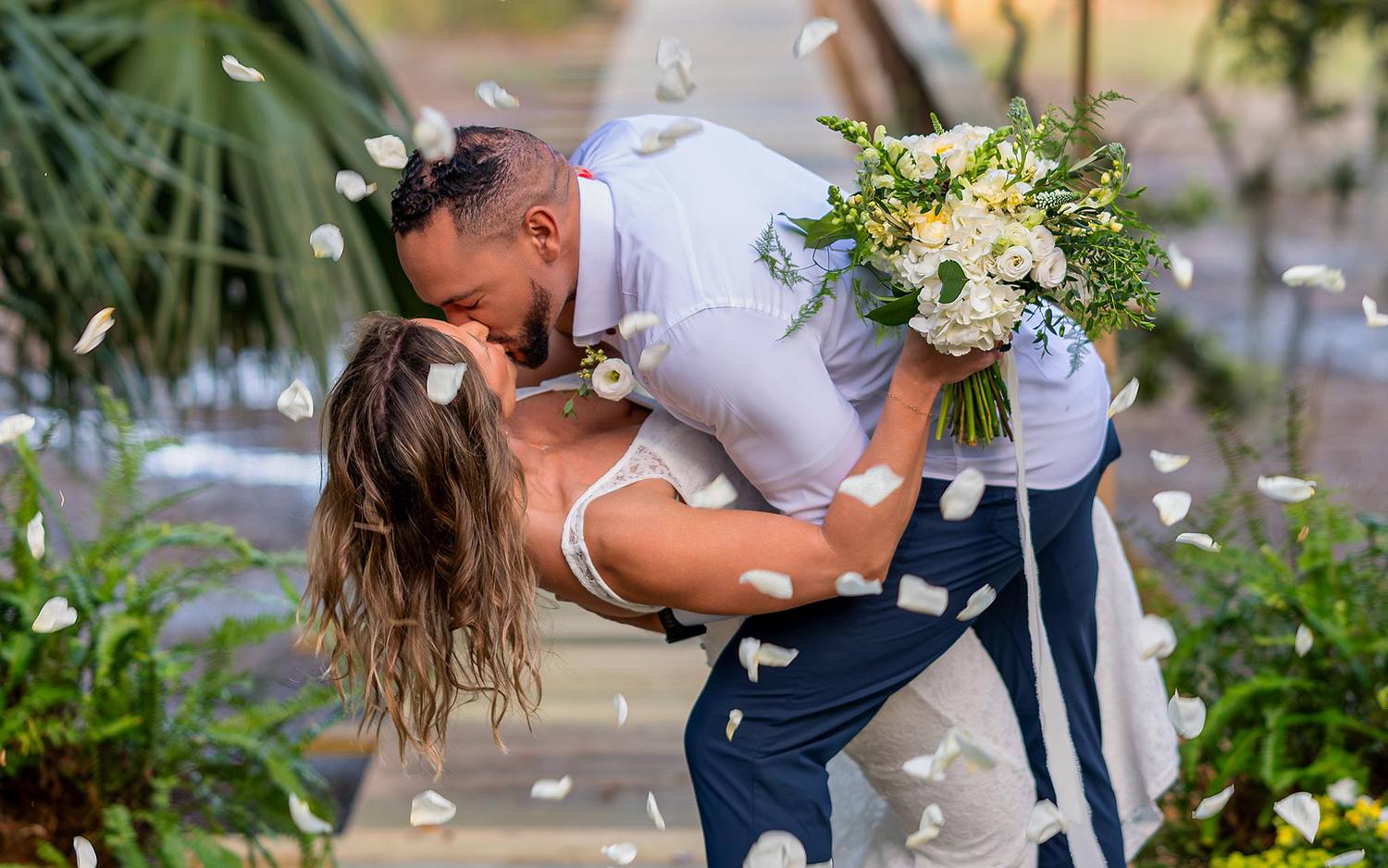 Bride and groom sharing their first wedding kiss on a dock in Bluffton, South Carolina, during their outdoor wedding photography session