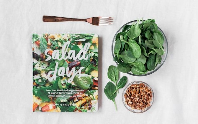 Salade dag kookboek naast heldere glazen kom met groente