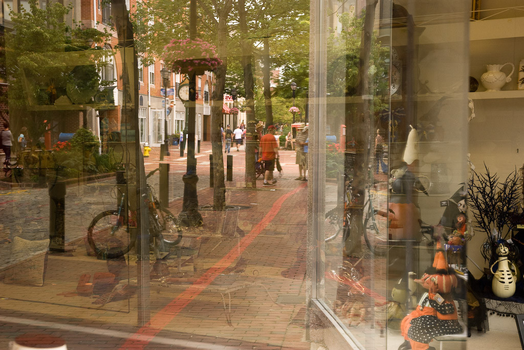 Halloween items in store window with brick sidewalk in front
