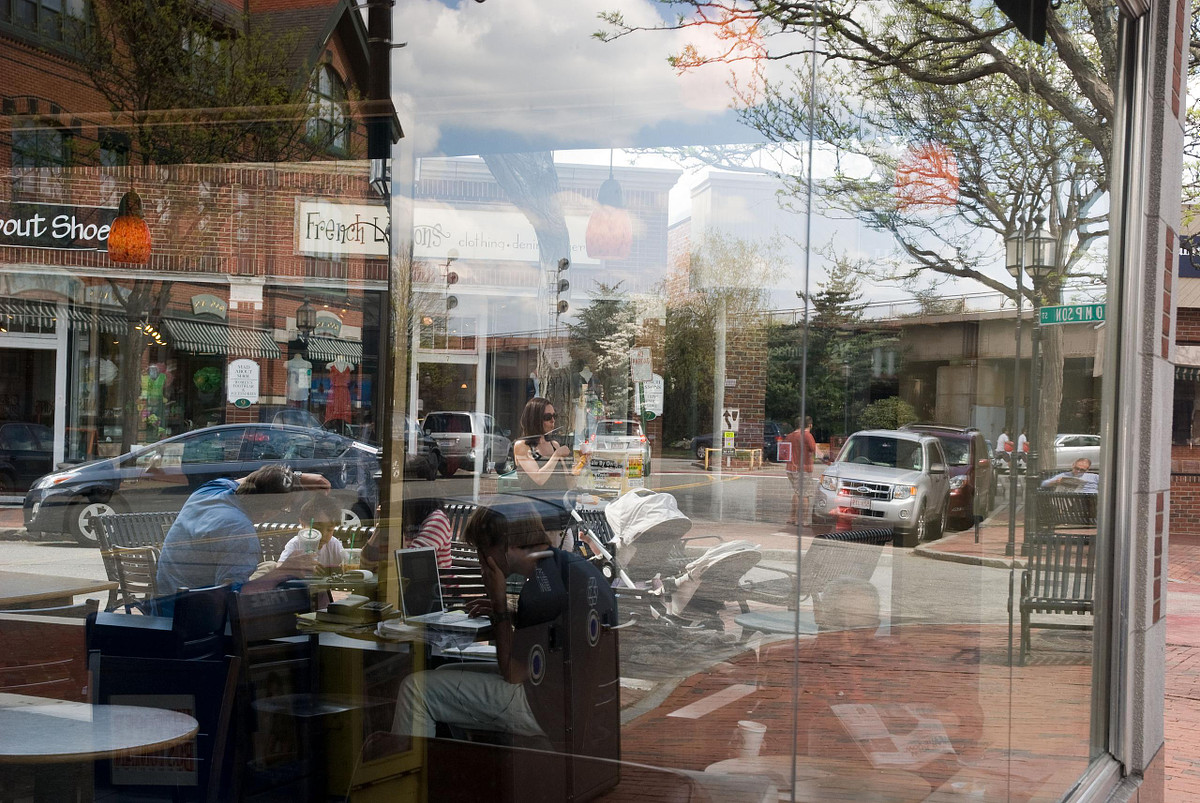People eating outside on a Winchester Main Street as seen reflected in window