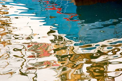 This abstract reflection features bold Icelandic colors from a Summer day in the northernmost village of the mainland. The twisting colored ribbons of red and green in the water are set against a turquoise blue lending it an almost Picasso-like abstraction.