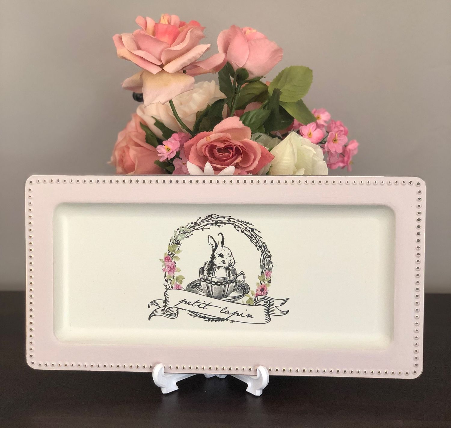 Decorative plate featuring a bunny illustration surrounded by a floral wreath, in soft pastel colors.