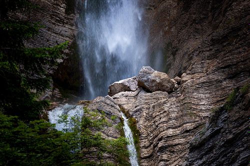 Cascade en forêt, roches et végétation.
