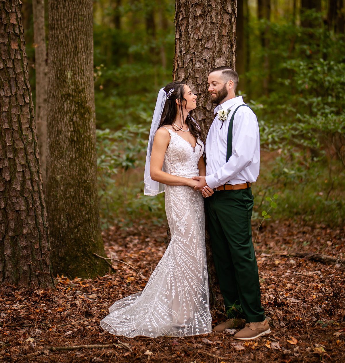 the couple standing in front of a tree in the forest of and eastern shore wedding during autumn