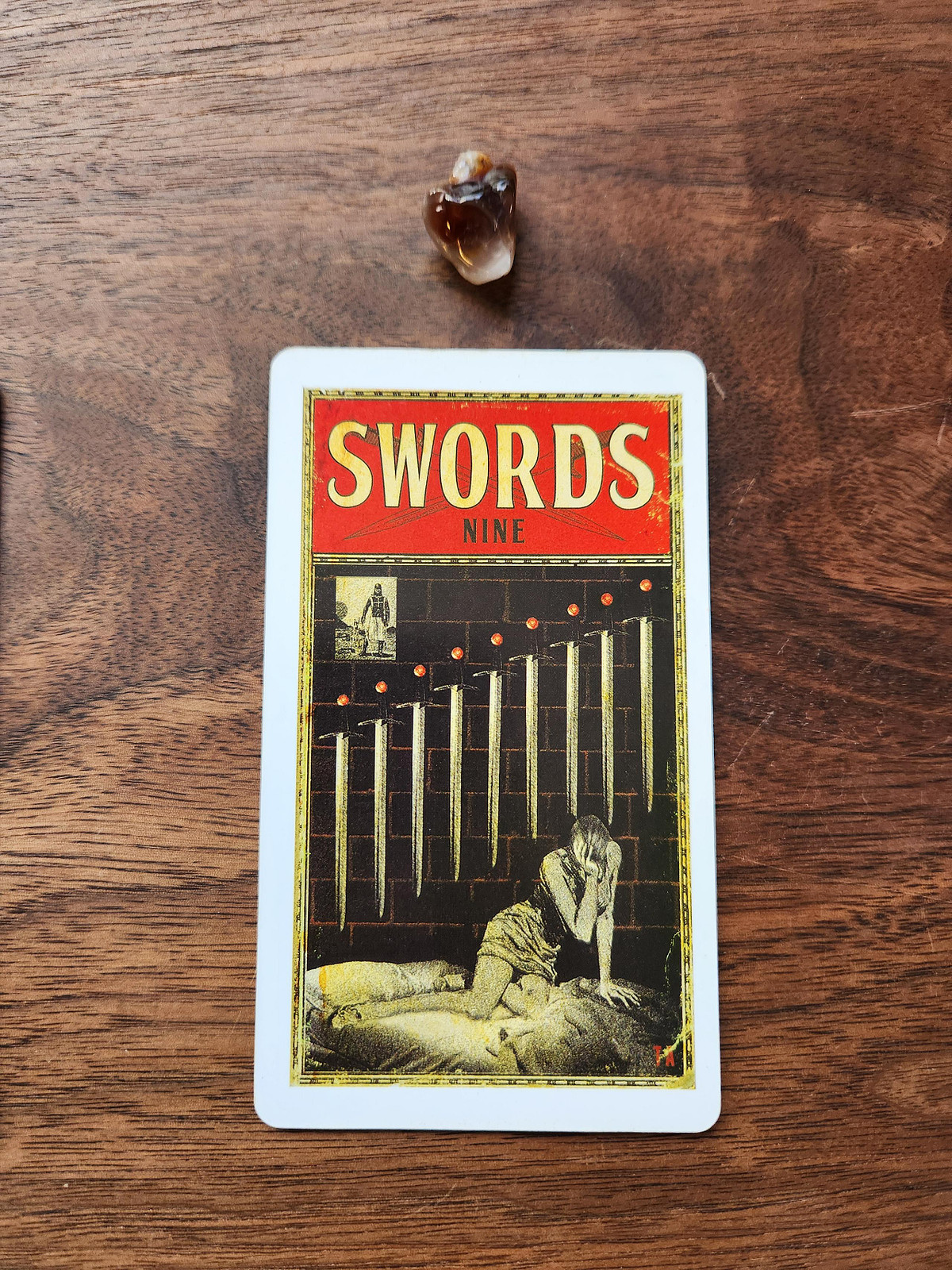 Nine of Swords Tarot card and a fire agate crystal
