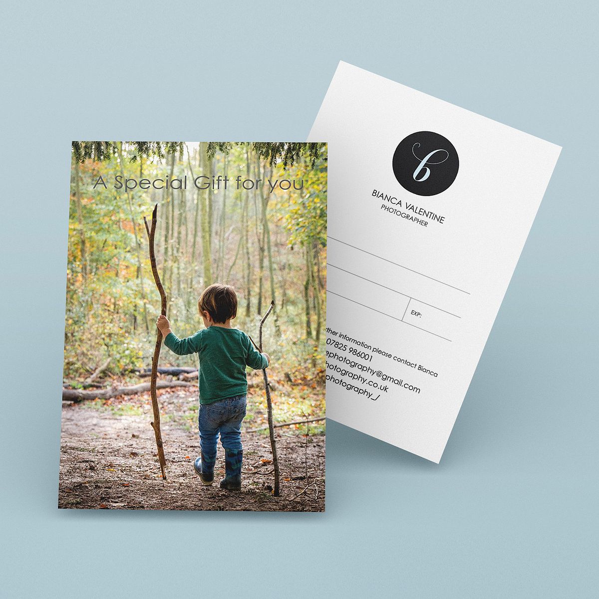 Gift voucher postcard with a photo of a little boy walking through a forest with 2 wooden staffs