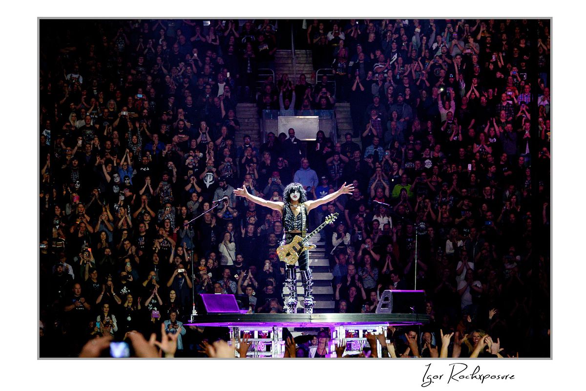 Paul Stanley standing on a small platform in the crowd with his hands raised