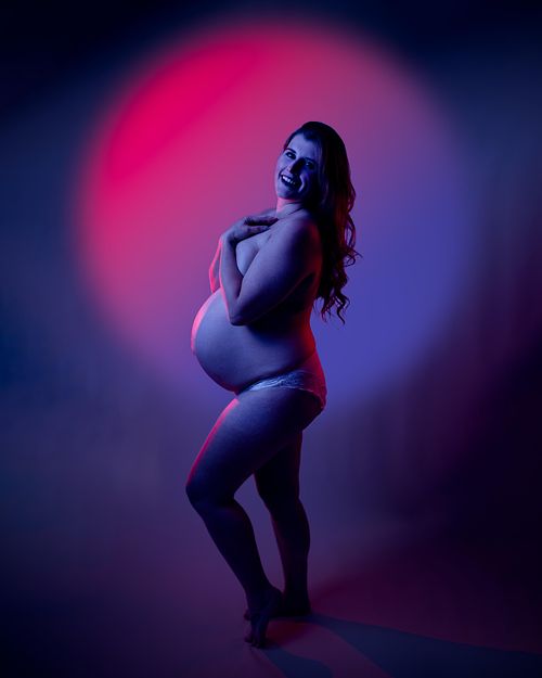 Neon partial nude of expecting mother in bold pink and blue.