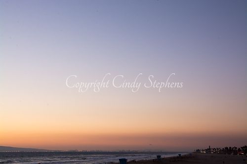 Pink and purple hues with colored lights along the California coastline