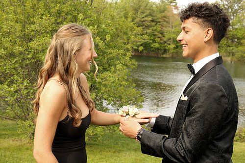 Boy puts corsage on girl's wrist during prom party