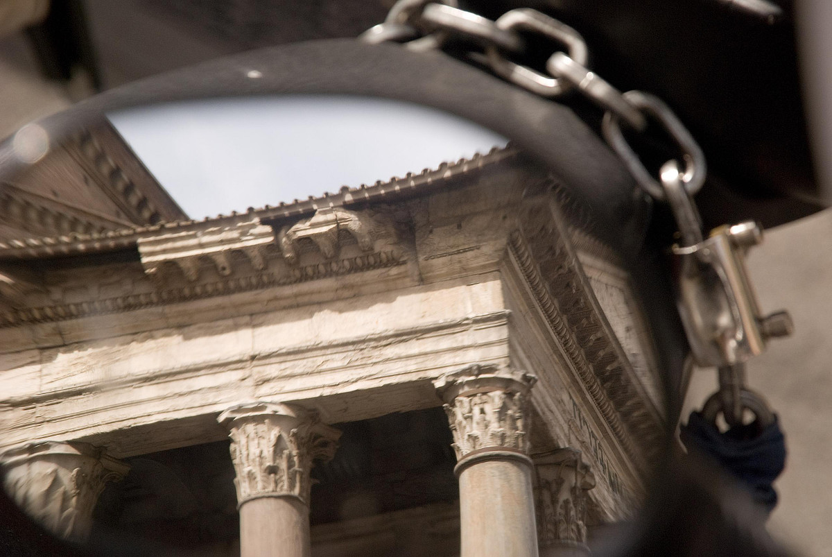 Reflection of columned historic building in motorcycle mirror