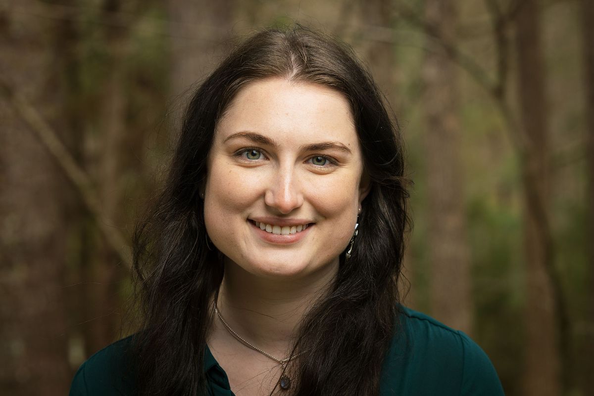 A woman posing for a headshot with a wooded background in Chapel Hill, NC