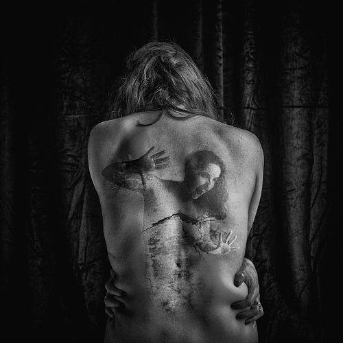 Photographie en noir et blanc d’une femme de dos, avec le double-exposé d’une autre femme emprisonnée dans son dos, symbolisant les émotions refoulées et la souffrance intérieure