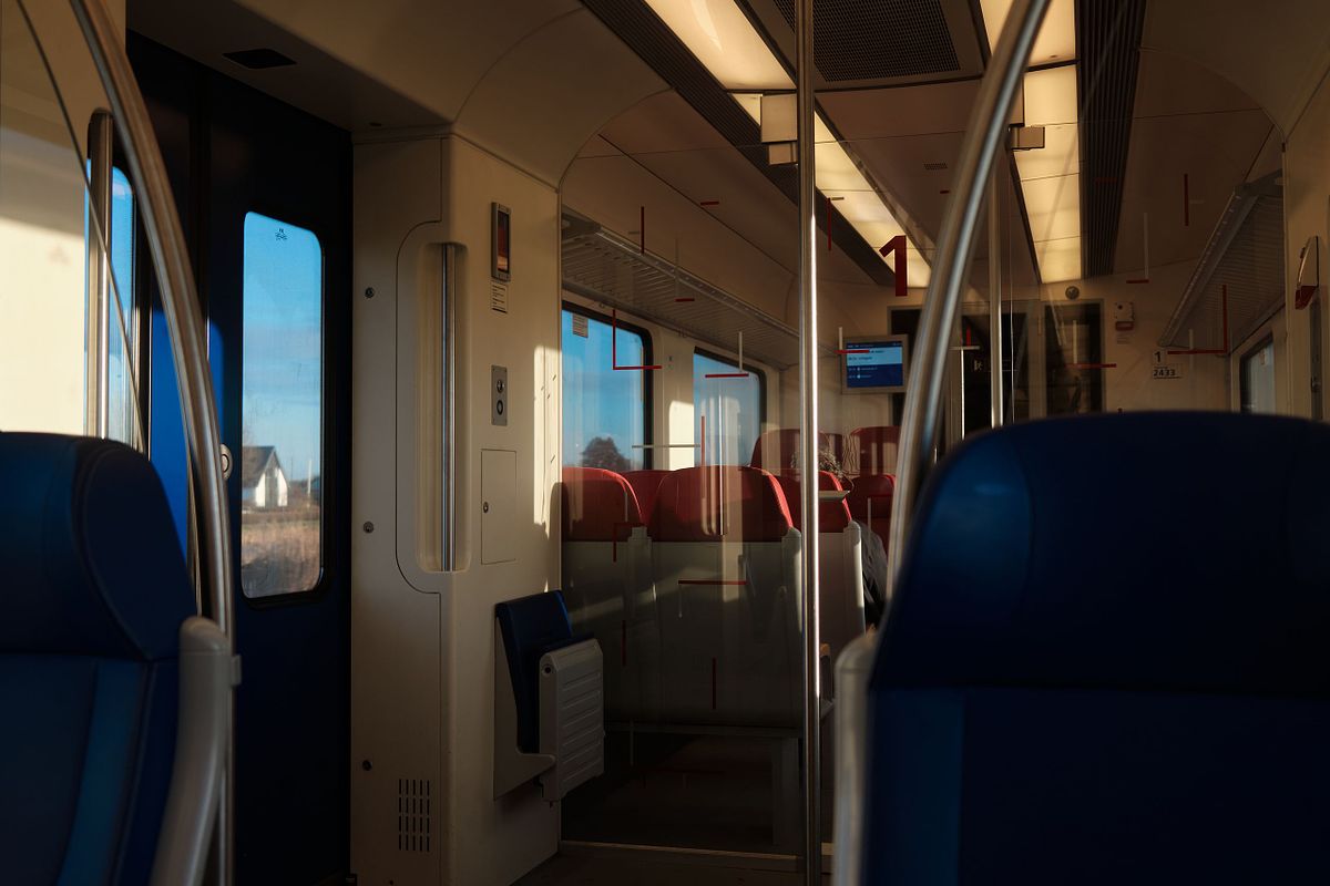Interior view of a Dutch train with blue and red seats, sunlight streaming through the windows, captured by photographer Sandeep Gajula