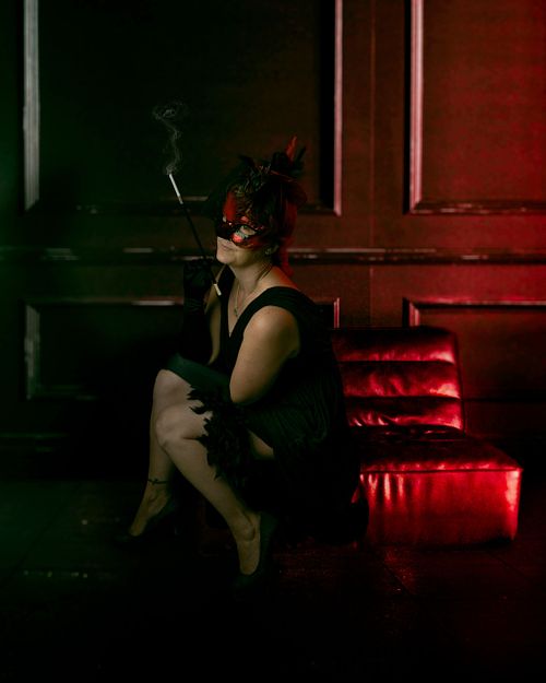 A witch in flapper clothing enjoys her cigarette while relaxing on a couch.