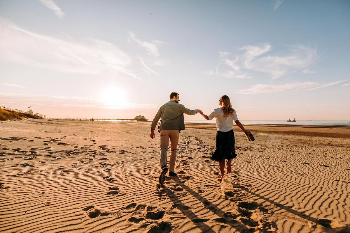 Hand in hand wandelen op het strand tijdens een verlovingsshoot