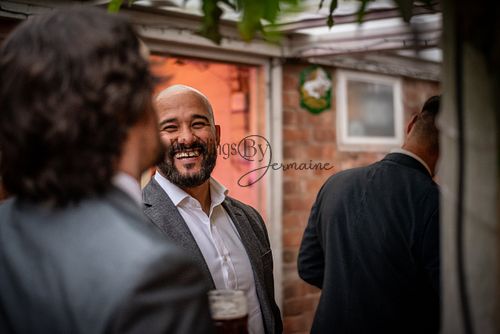 Wedding guest laughing and chatting at a relaxed back garden wedding in Hinckley, photographed by Weddings By Jermaine.