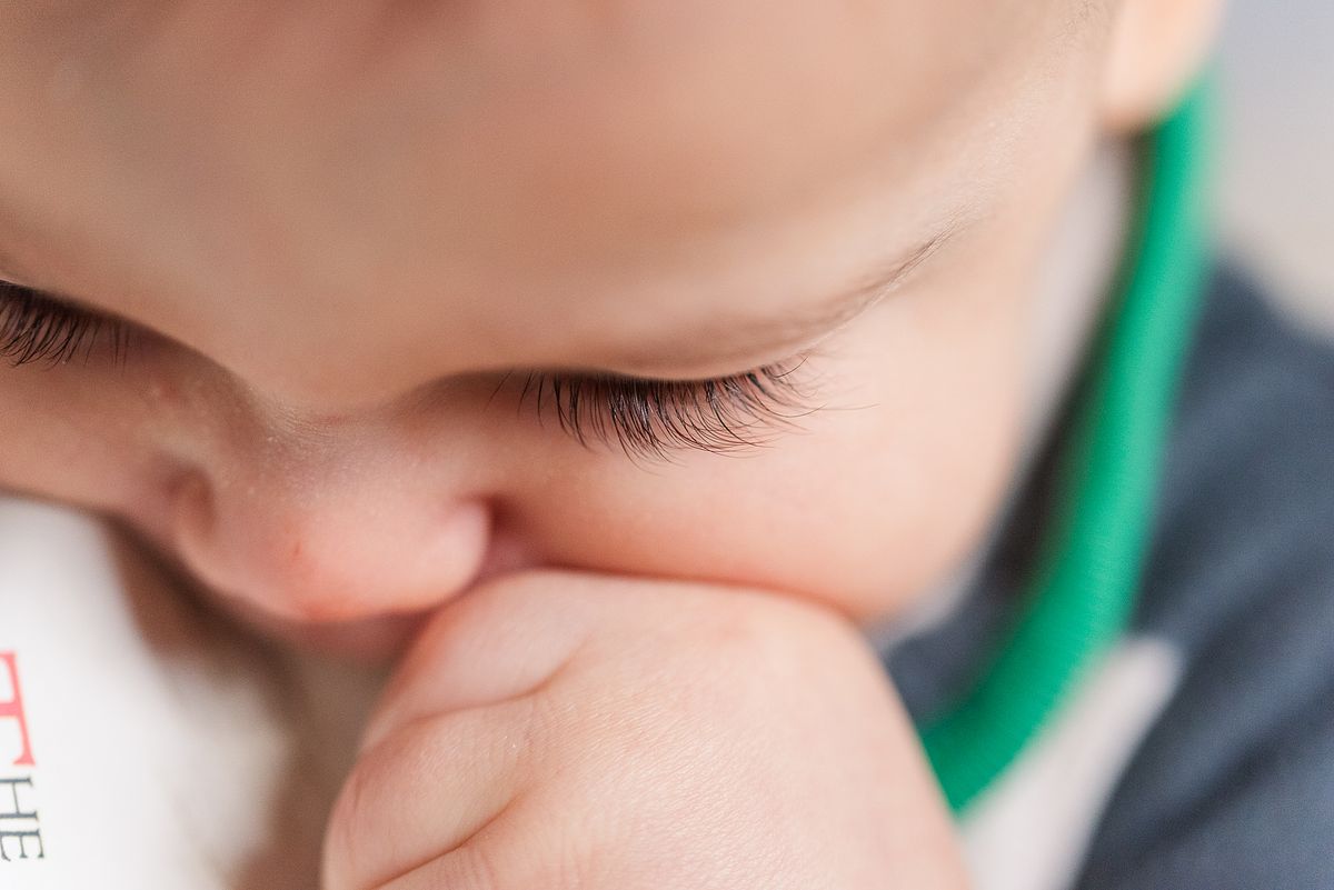 up-close of baby holding and trying to bite a book, eyelash details, in Cranberry Township, PA