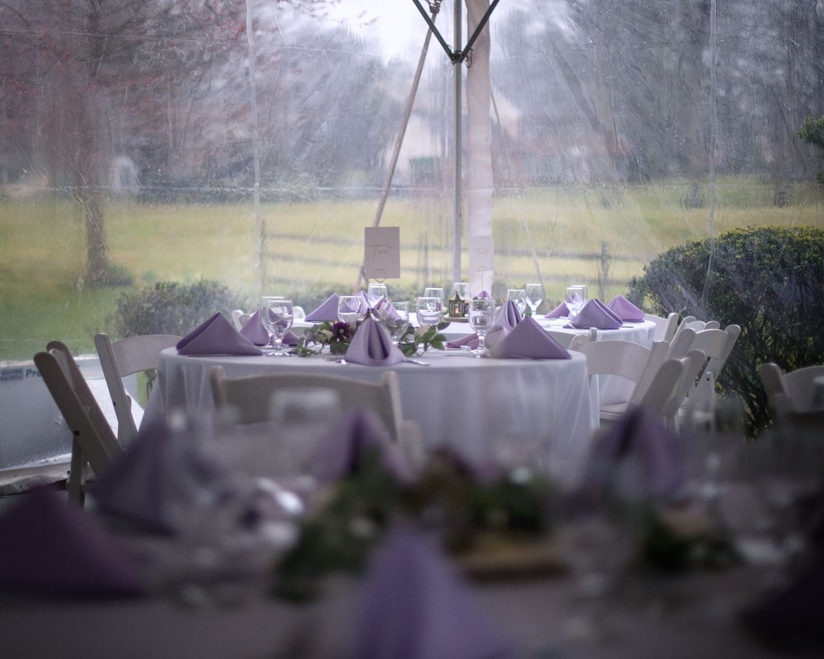 a covered outside dinning room at a wedding venue, covered because of rain