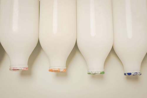 Glass milk bottles viewed from below, lined up against a light background