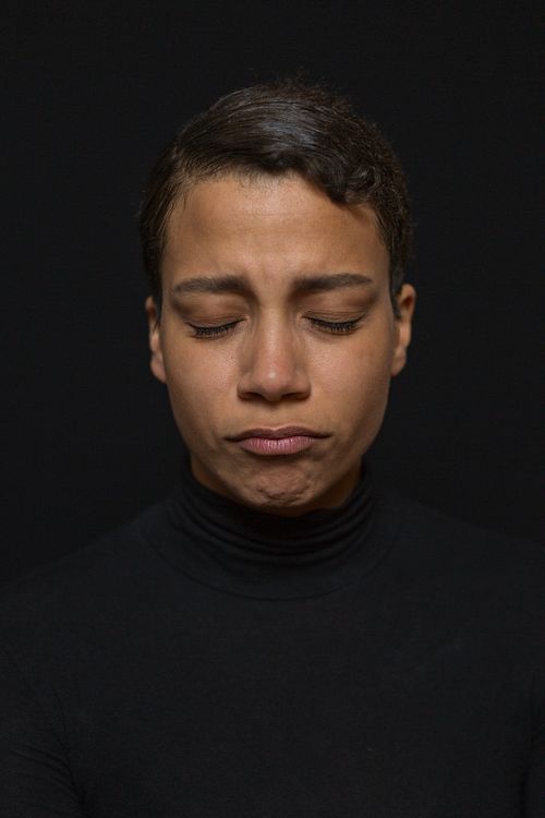 A headshot of a woman with a frowned face in a black turtleneck.