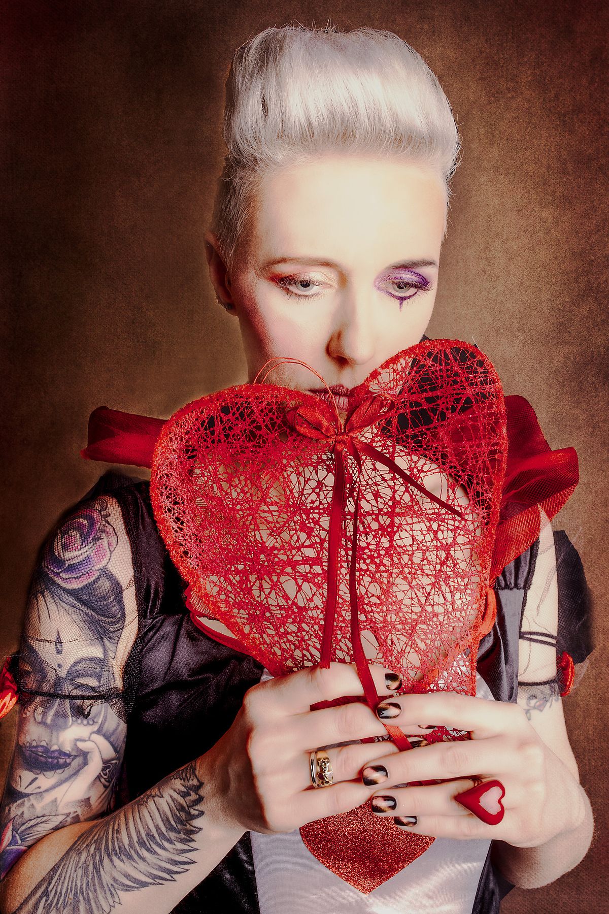 photo tarot Reine de Cœur, femme triste cachée derrière un cœur dans un monde féerique