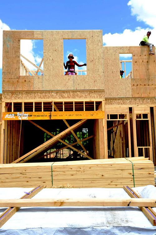 Construction workers framing a home under clear skies.