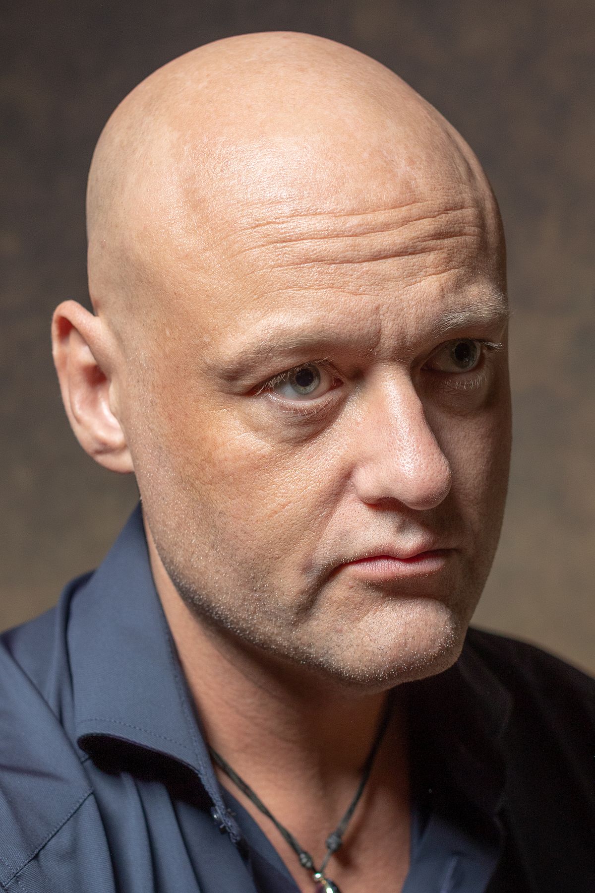 Man i m&ouml;rk skjorta i varm tonad studio, &auml;rlig och n&auml;ra blick