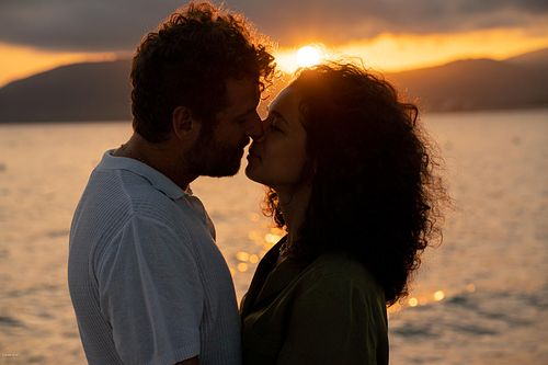 "coppia si guarda al tramonto in spiaggia ad Alghero"