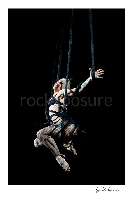 Vertical color image of Pink suspended high above the stage on ropes with one arm outstretched during a dramatic live performance
