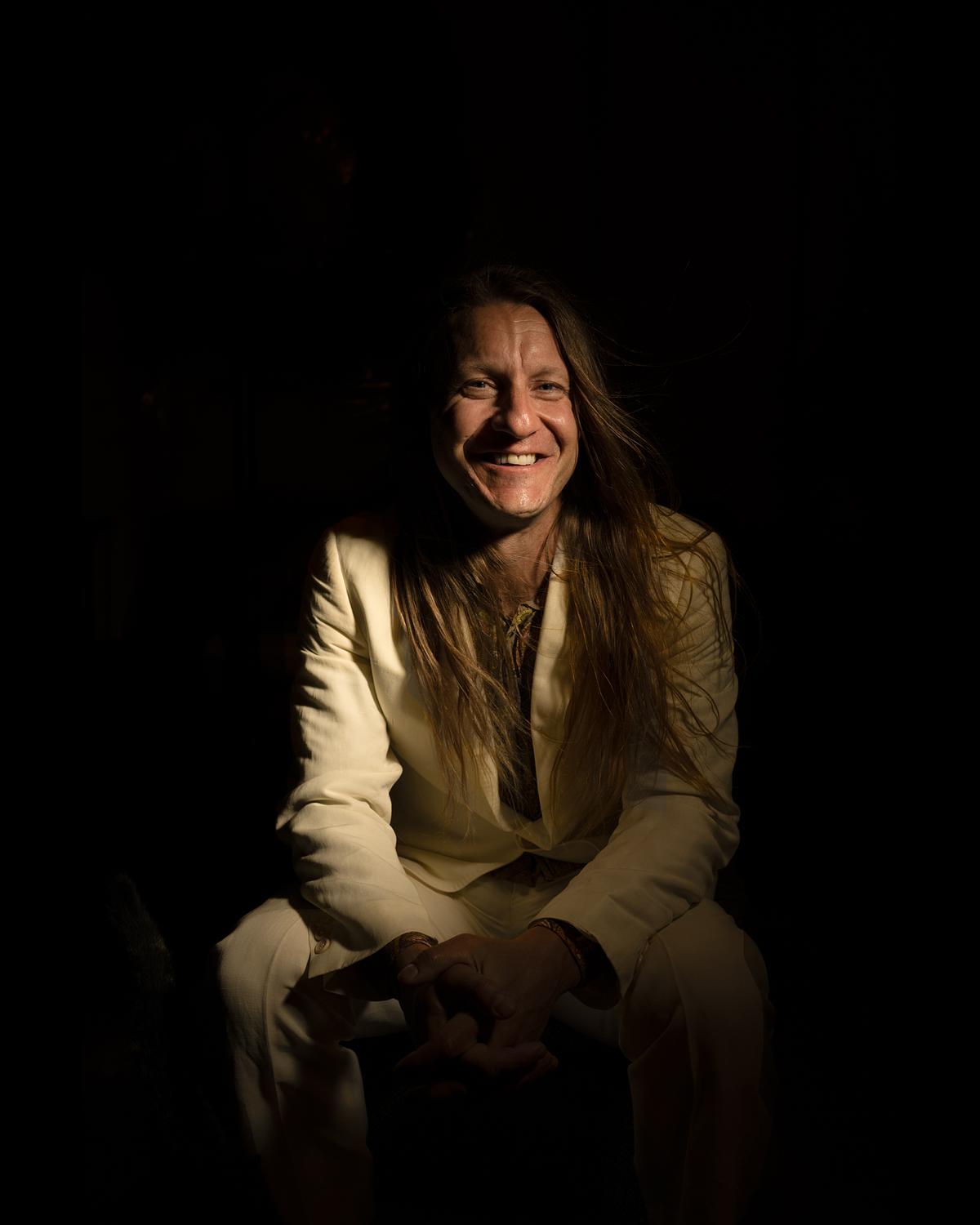 Portrait of a golden man with long hair smiling like the sun.
