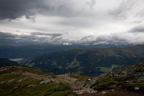 Vallée rocheuse avec cours d’eau, ciel nuageux.