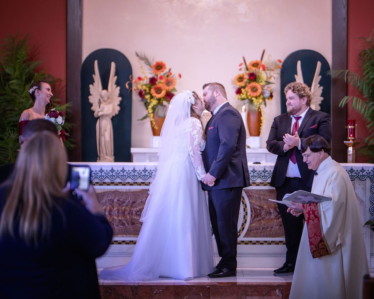 bride and groom kissing in front of the altar after catholic ceremony at st. lukes, lewes, delaware