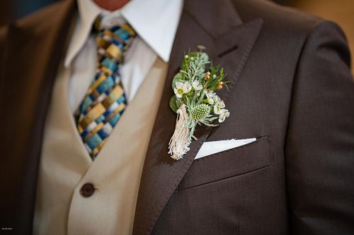 "dettagli abito marrone dello sposo con bottoniera"