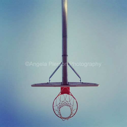 A basketball hoop shot from under the hoop looking up into the sky
