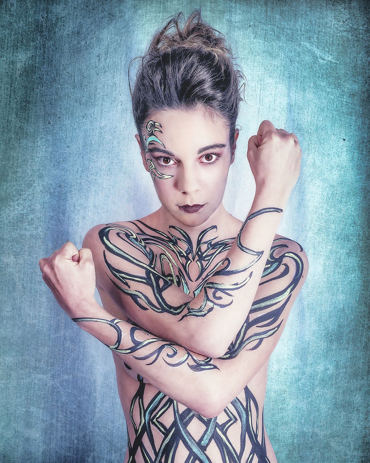 photo tarot Light Warrior, femme nue bras croisés avec lignes peintes sur le corps et fond bleu lumineux