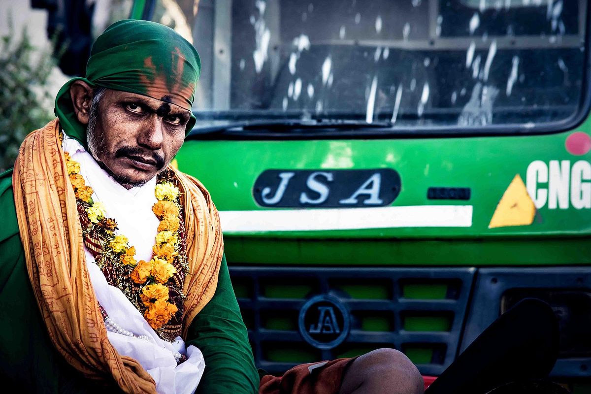 man, sadhu, garland, bus in background