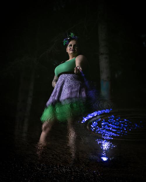 A powerful woman sprinkles magic into her reflection in the water.