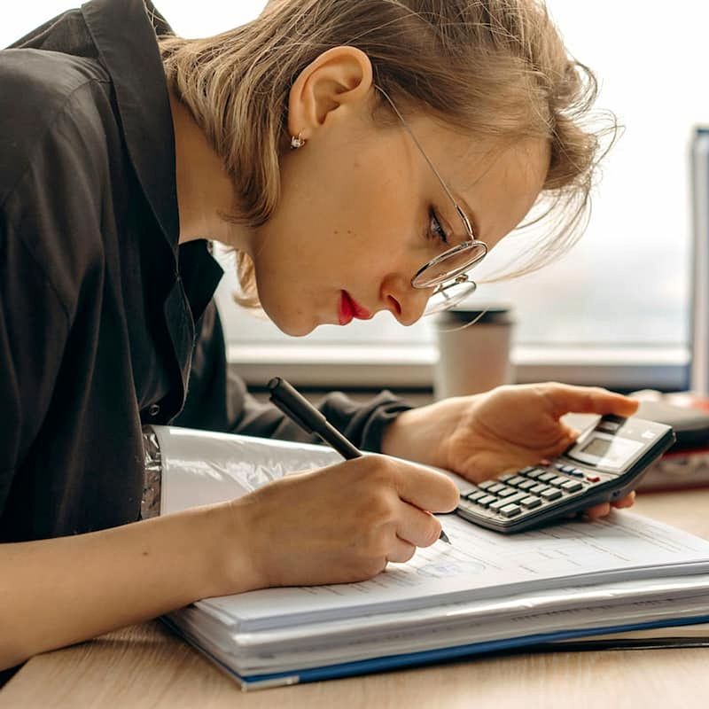 Menopausal woman using calculator while taking notes