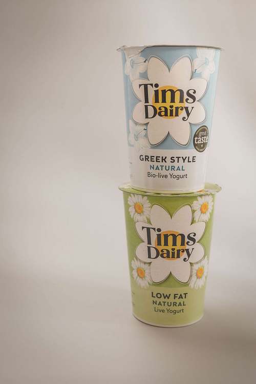 Stacked yoghurt pots with branded labels on a neutral background
