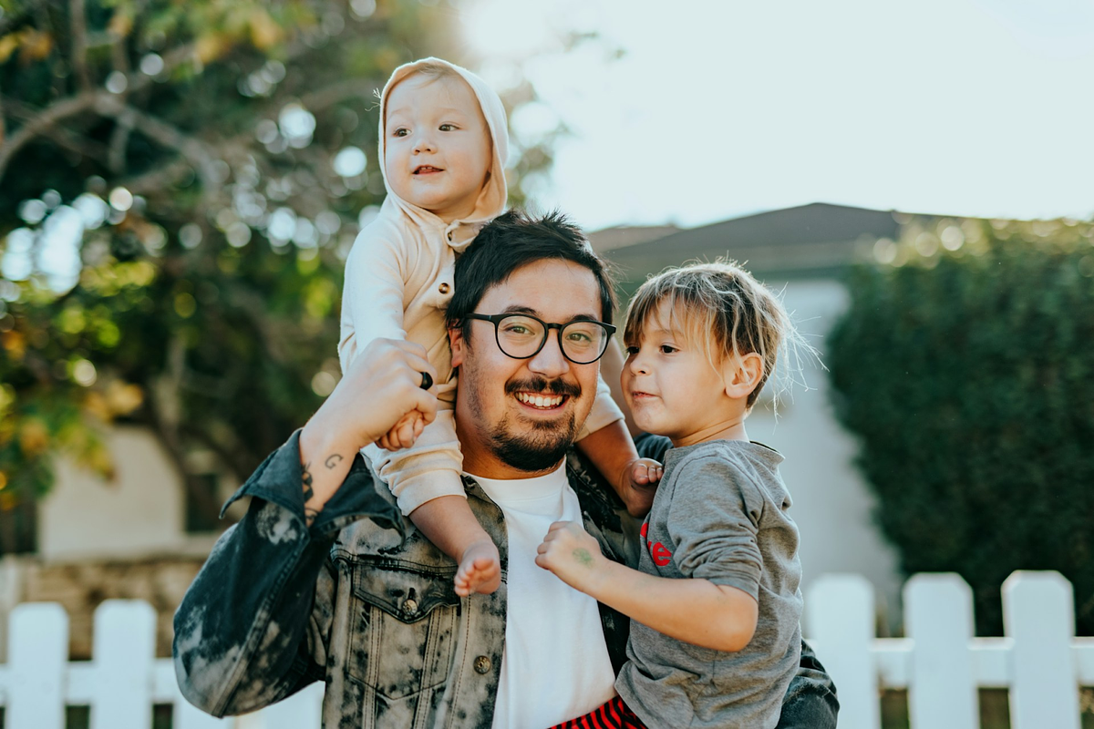 Hombre con camisa blanca cargando a una niña con camisa gris